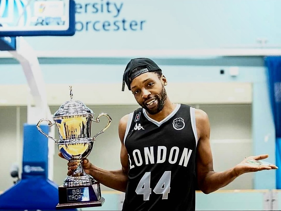 Coach Shane holding a BBL trophy during his professional basketball career